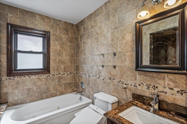 bathroom featuring toilet, tile walls, a jetted tub, and vanity