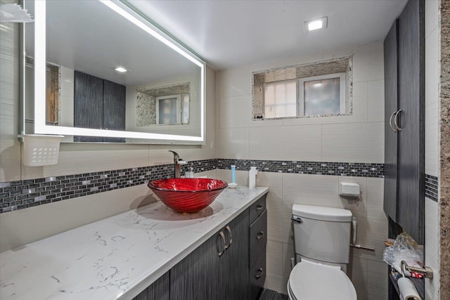 bathroom featuring toilet, vanity, and decorative backsplash
