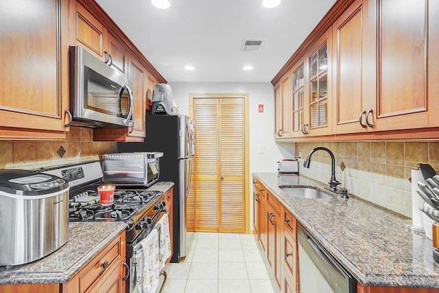 kitchen with appliances with stainless steel finishes, visible vents, light stone countertops, and a sink