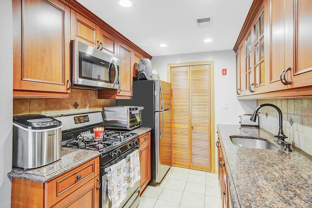 kitchen featuring tasteful backsplash, stone counters, appliances with stainless steel finishes, and a sink