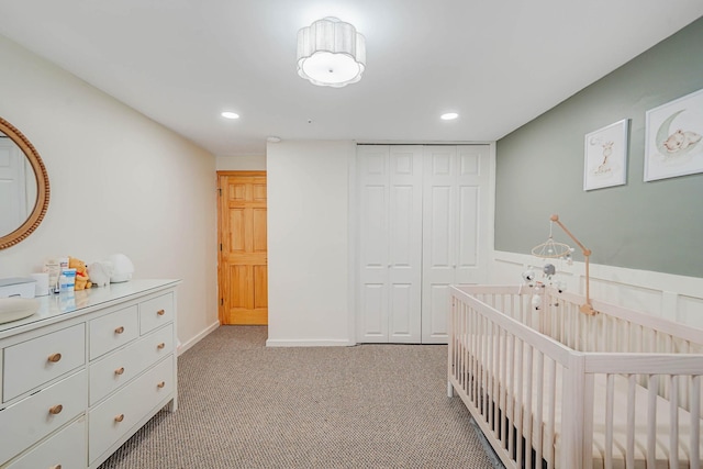bedroom featuring recessed lighting, a nursery area, light carpet, and a closet