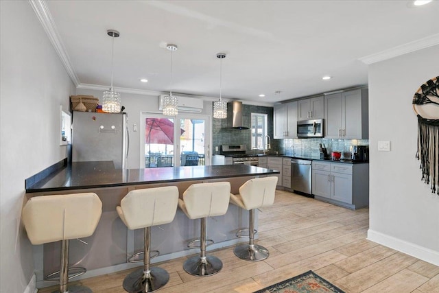 31 Arthur St, Baldwin, NY 11510 - kitchen featuring wall chimney exhaust hood, stainless steel appliances, a peninsula, dark countertops, and a kitchen bar