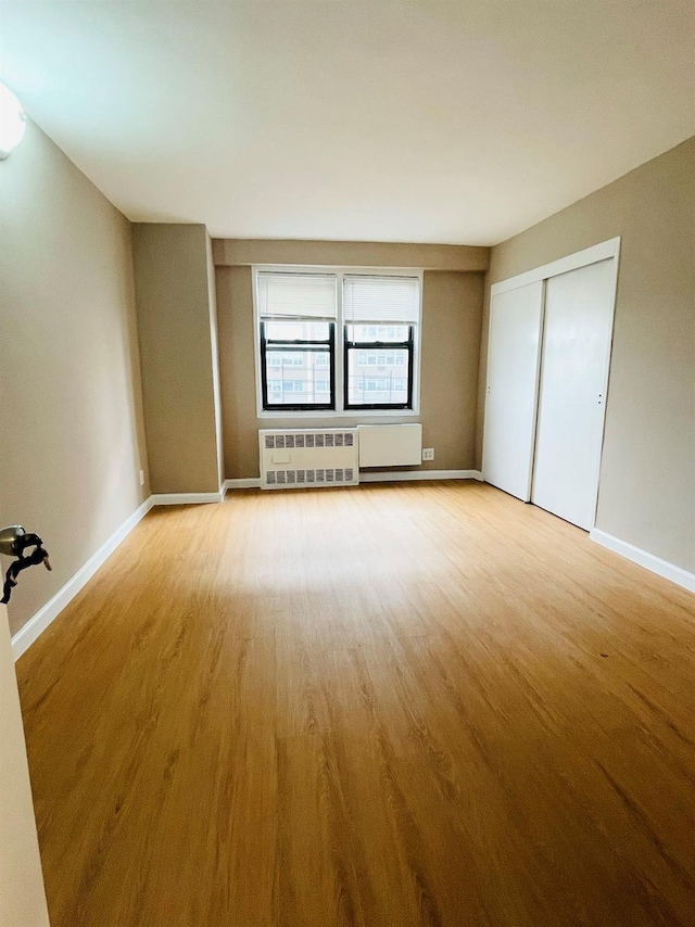 interior space with light wood-type flooring, baseboards, and radiator heating unit