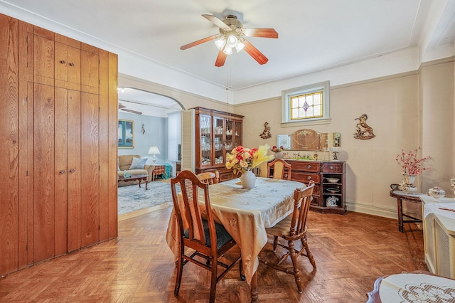 dining area with arched walkways, ceiling fan, and baseboards