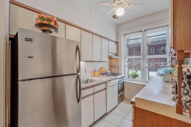 kitchen featuring a sink, freestanding refrigerator, white dishwasher, light countertops, and under cabinet range hood
