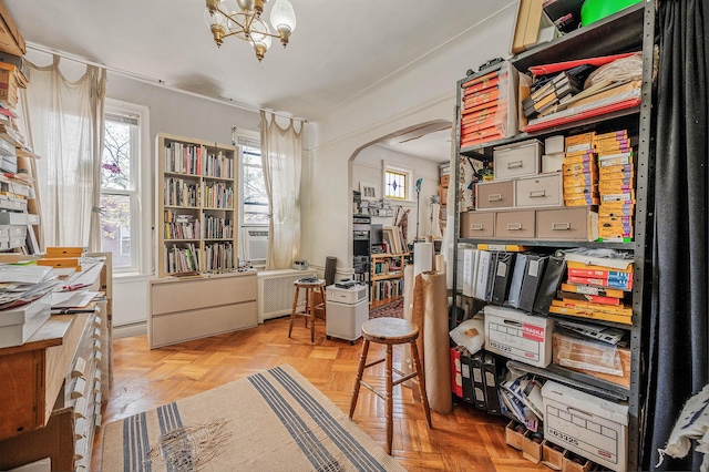 office space featuring arched walkways, a chandelier, and a healthy amount of sunlight