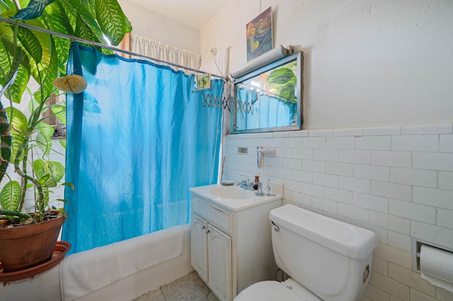 full bath featuring tile patterned flooring, toilet, vanity, shower / tub combo with curtain, and tile walls
