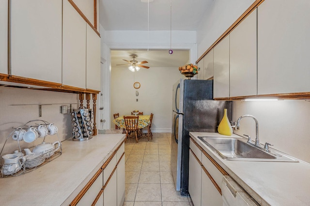 kitchen with light countertops, freestanding refrigerator, decorative backsplash, and a sink