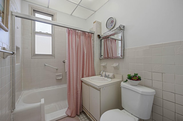 full bath with toilet, tile walls, vanity, and shower / bathtub combination with curtain