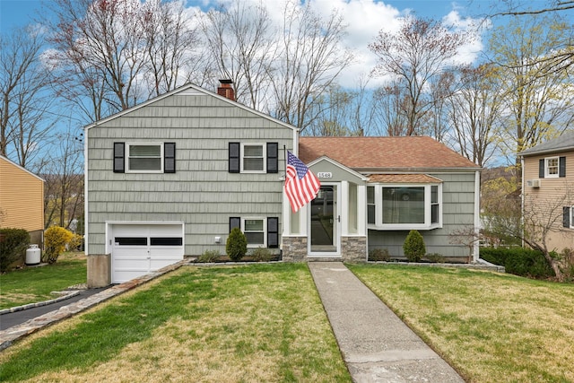 split level home with an attached garage, driveway, a chimney, and a front yard