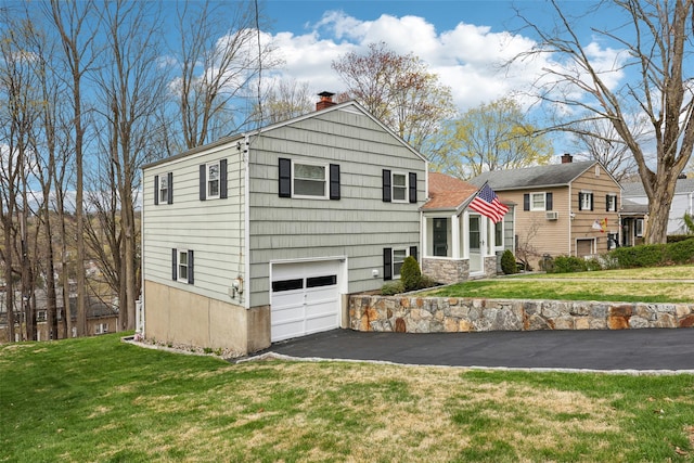 view of front of home with a garage, aphalt driveway, a front yard, and a chimney