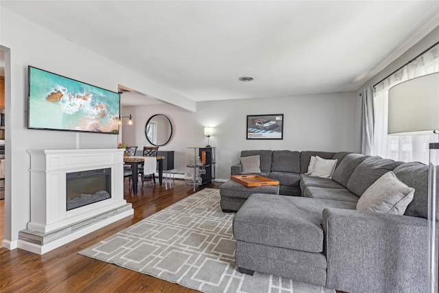living area with baseboards, visible vents, and wood finished floors