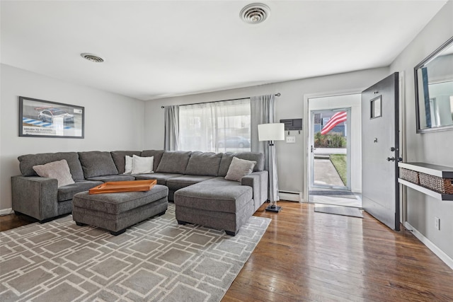living room featuring baseboards, visible vents, wood finished floors, and a baseboard radiator