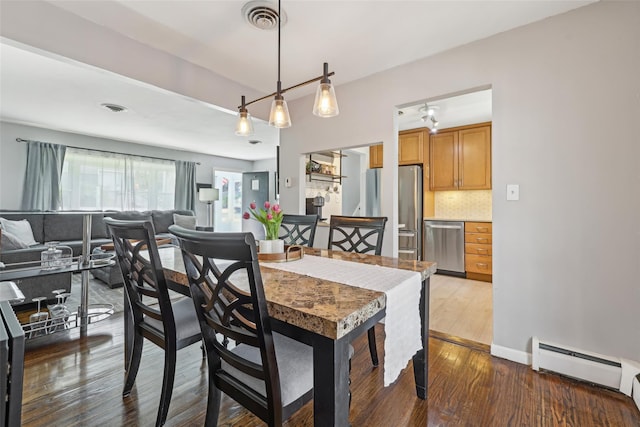dining room featuring a baseboard heating unit, wood finished floors, and visible vents