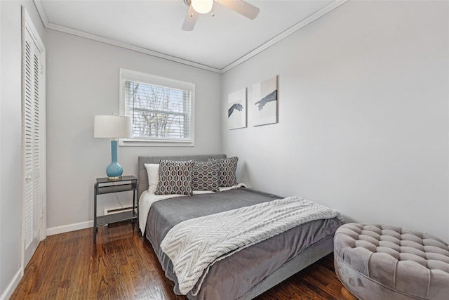 bedroom featuring crown molding, baseboards, wood finished floors, and a closet