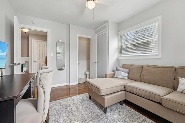 living area with baseboards, ceiling fan, and wood finished floors