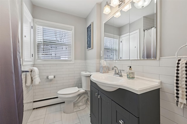 bathroom with tile walls, tile patterned flooring, a baseboard heating unit, and a wealth of natural light