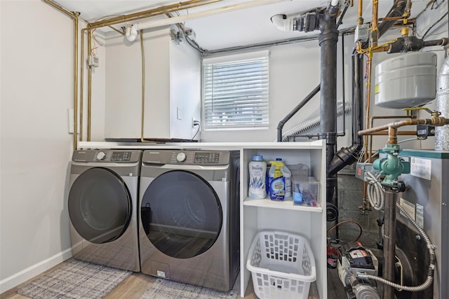 laundry room with wood finished floors, laundry area, baseboards, and washing machine and dryer
