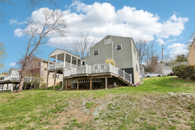 back of property with a lawn, a wooden deck, and stairs