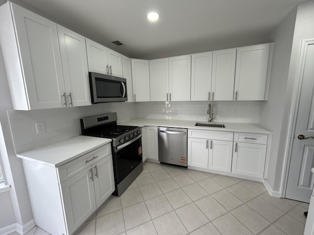 kitchen with tasteful backsplash, white cabinets, a sink, light countertops, and stainless steel appliances
