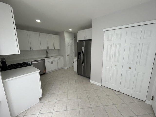 kitchen featuring light tile patterned floors, recessed lighting, appliances with stainless steel finishes, light countertops, and a sink