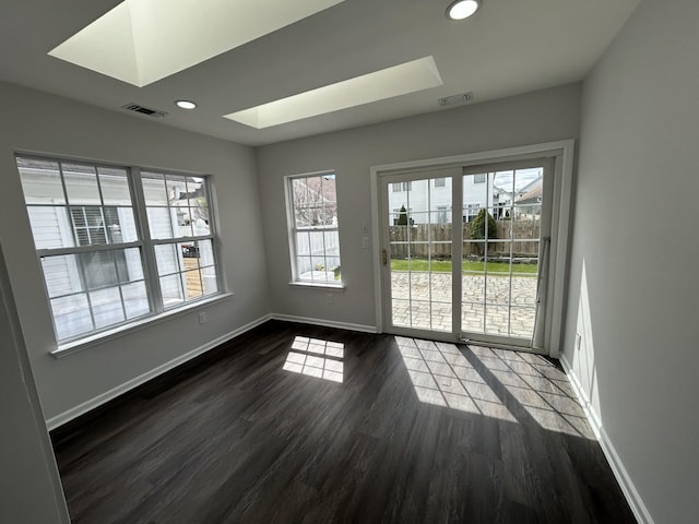 empty room featuring visible vents, recessed lighting, a skylight, dark wood-style flooring, and baseboards