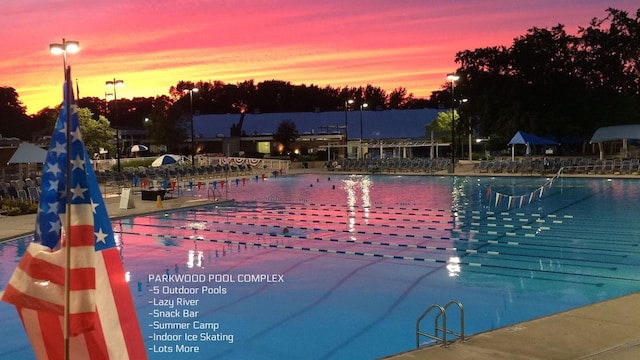 pool at dusk featuring a community pool