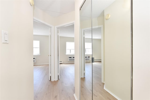 hall featuring an AC wall unit, a wall unit AC, baseboard heating, and light wood-style floors