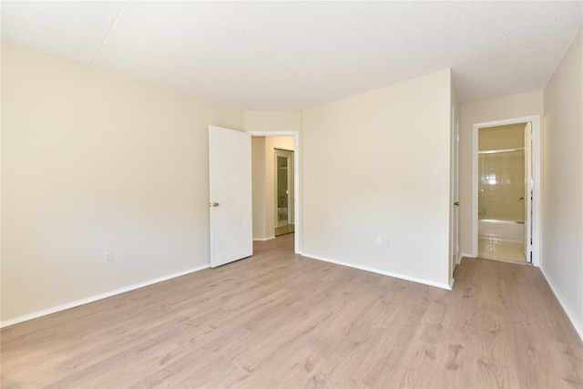 spare room with baseboards and light wood-type flooring