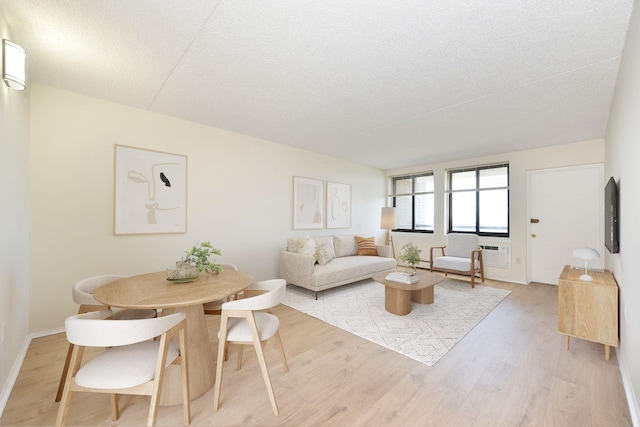 living room featuring light wood finished floors, a textured ceiling, and baseboards