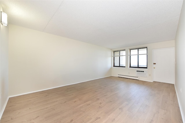 25-56 120th St Unit 2C, Flushing, NY 11354 - unfurnished room featuring baseboard heating, light wood-type flooring, a wall mounted air conditioner, and a textured ceiling