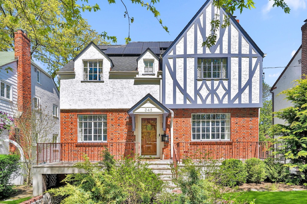 345 E Grand St, Mount Vernon, NY 10552 - tudor home featuring brick siding, roof mounted solar panels, stucco siding, and roof with shingles