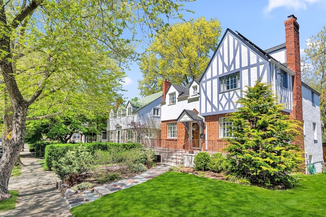 exterior space with a lawn, brick siding, a chimney, and stucco siding