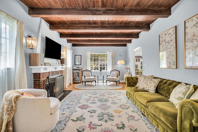 living area with a brick fireplace, arched walkways, wood finished floors, beamed ceiling, and wood ceiling