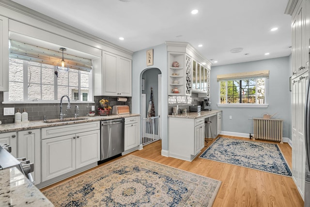 kitchen with arched walkways, tasteful backsplash, dishwasher, radiator heating unit, and white cabinetry