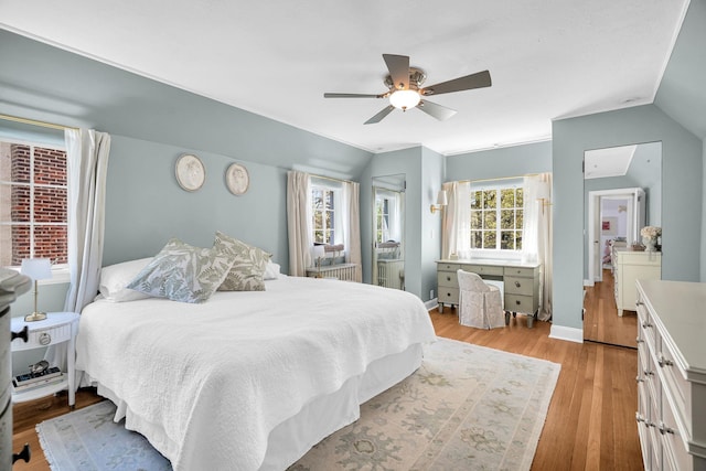 bedroom with baseboards, a ceiling fan, light wood-style flooring, and lofted ceiling