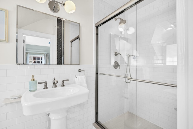bathroom featuring wainscoting, tile walls, and a stall shower
