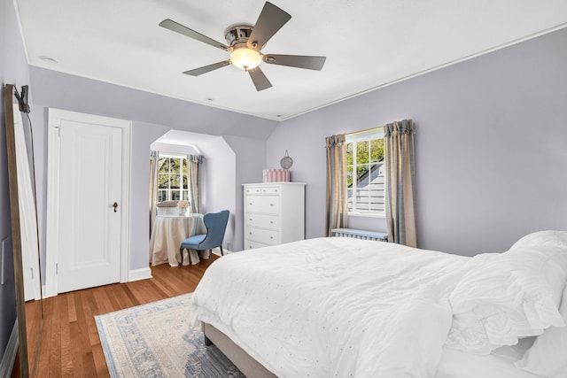 bedroom featuring ceiling fan, wood finished floors, and multiple windows