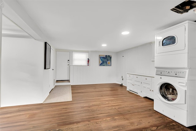 laundry room featuring stacked washer / drying machine, recessed lighting, wood finished floors, and laundry area