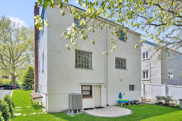 back of property with fence, stucco siding, a yard, and cooling unit