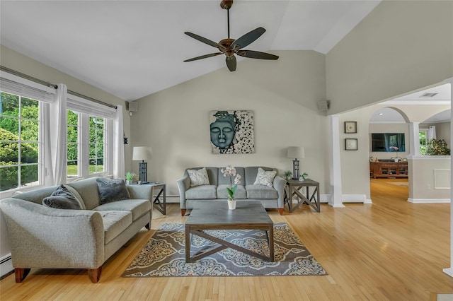 living room with light wood-style flooring, arched walkways, baseboard heating, ceiling fan, and high vaulted ceiling