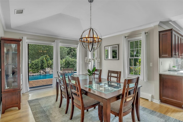 dining space with an inviting chandelier, crown molding, light wood-style floors, and visible vents