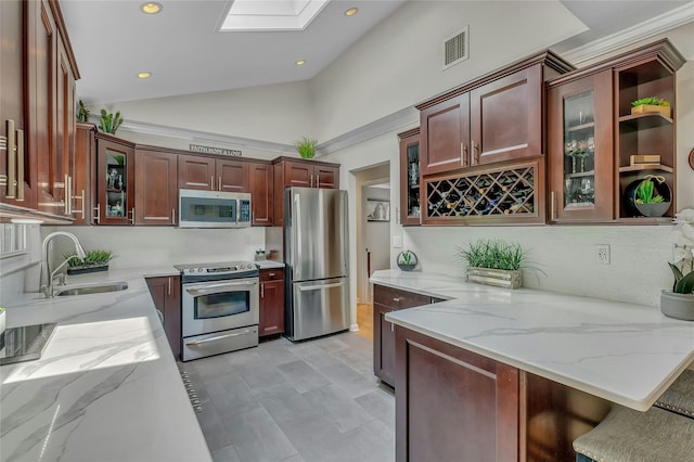 kitchen featuring glass insert cabinets, light stone counters, stainless steel appliances, and a sink