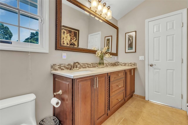 bathroom featuring tile patterned flooring, double vanity, toilet, a sink, and tasteful backsplash