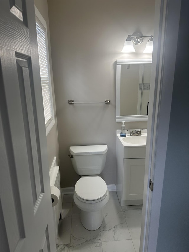 bathroom with marble finish floor, toilet, vanity, and baseboards