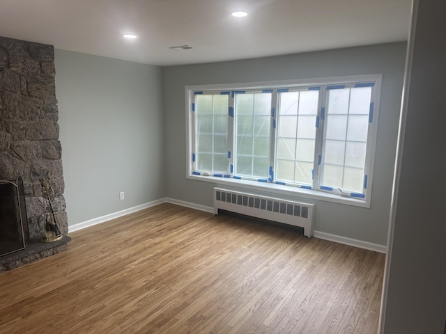 unfurnished living room with baseboards, visible vents, recessed lighting, radiator heating unit, and wood finished floors