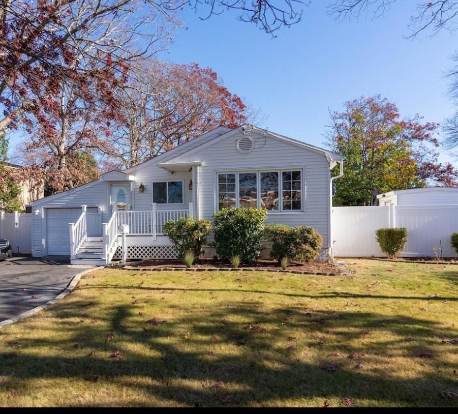view of front of property with fence, a front lawn, aphalt driveway, and a garage