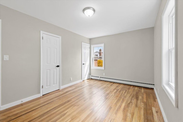 unfurnished bedroom with baseboards, baseboard heating, and light wood-style flooring