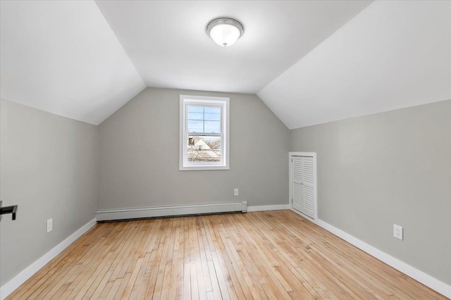 additional living space featuring vaulted ceiling, baseboards, wood-type flooring, and a baseboard heating unit