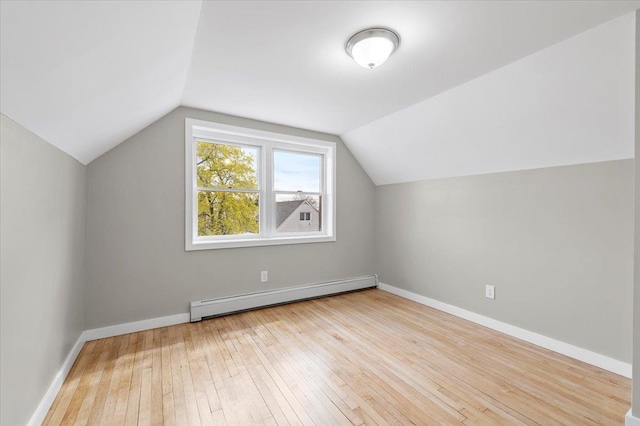 additional living space featuring baseboards, vaulted ceiling, baseboard heating, and hardwood / wood-style floors